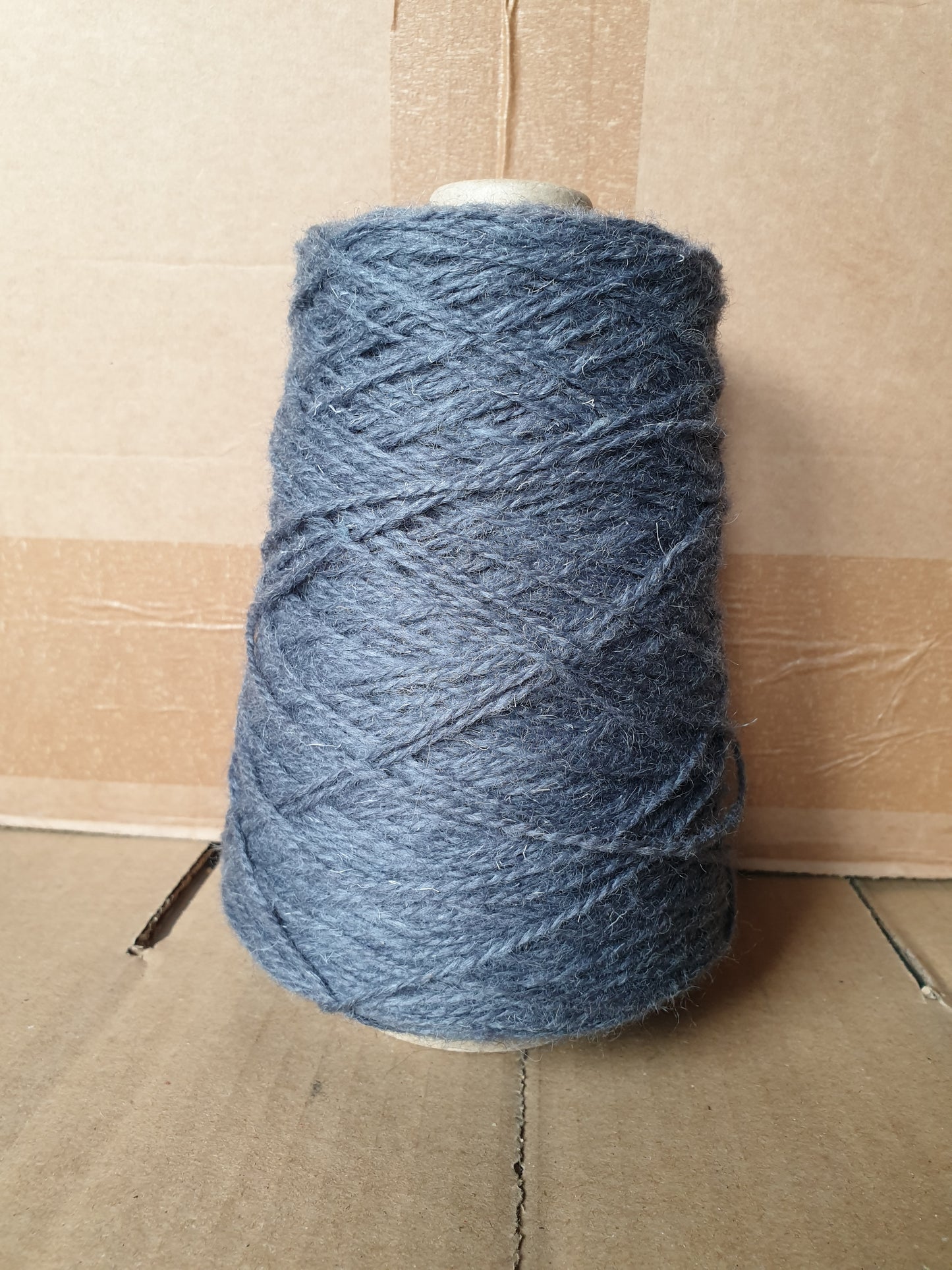 A greyish blue cone of rug yarn