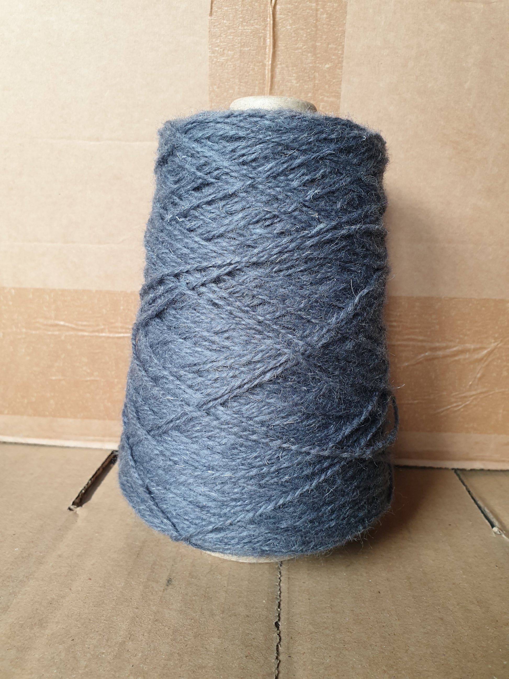 A greyish blue cone of rug yarn