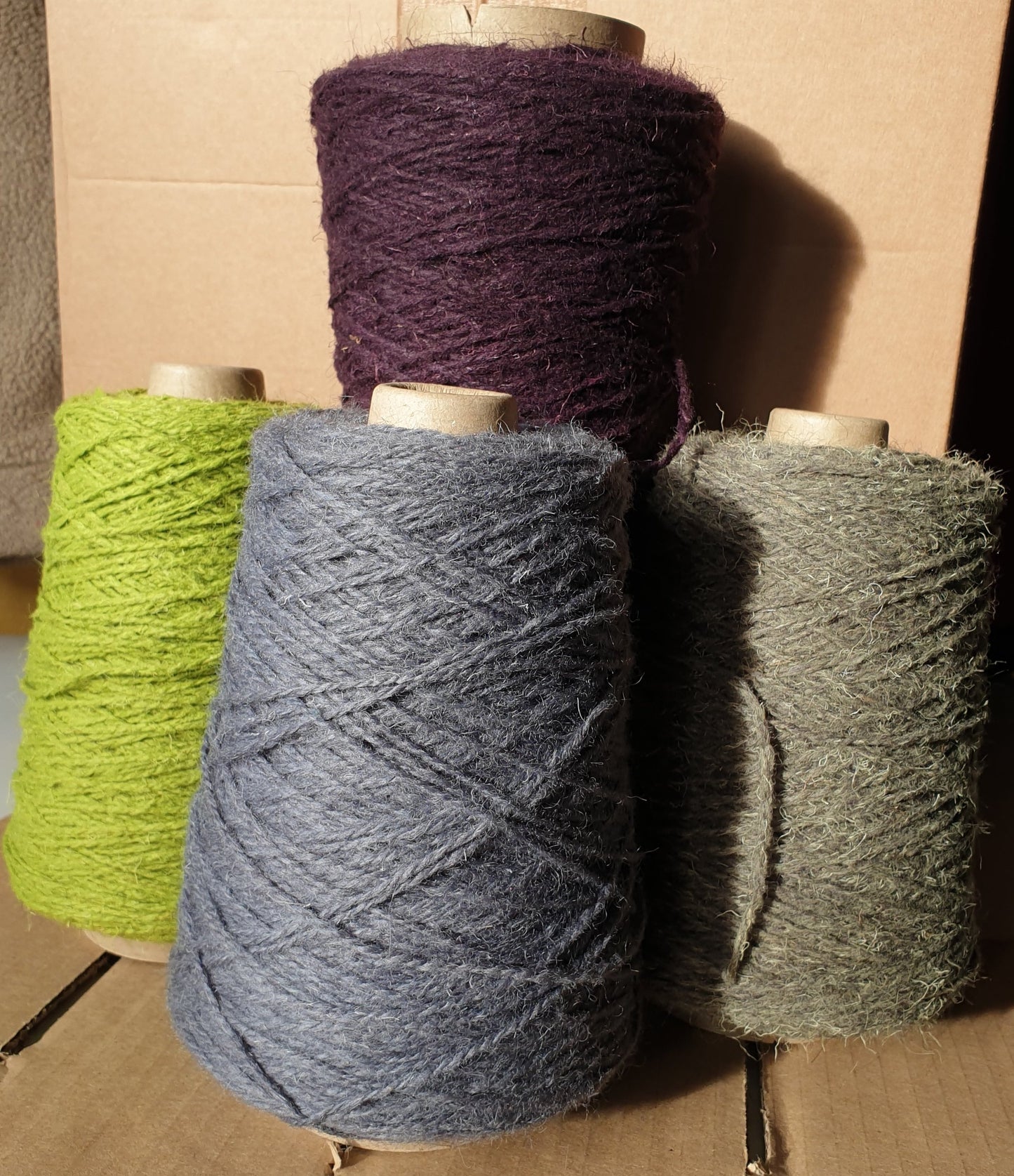 Cones of blue-grey, spring green, purple and marram green rug yarn
