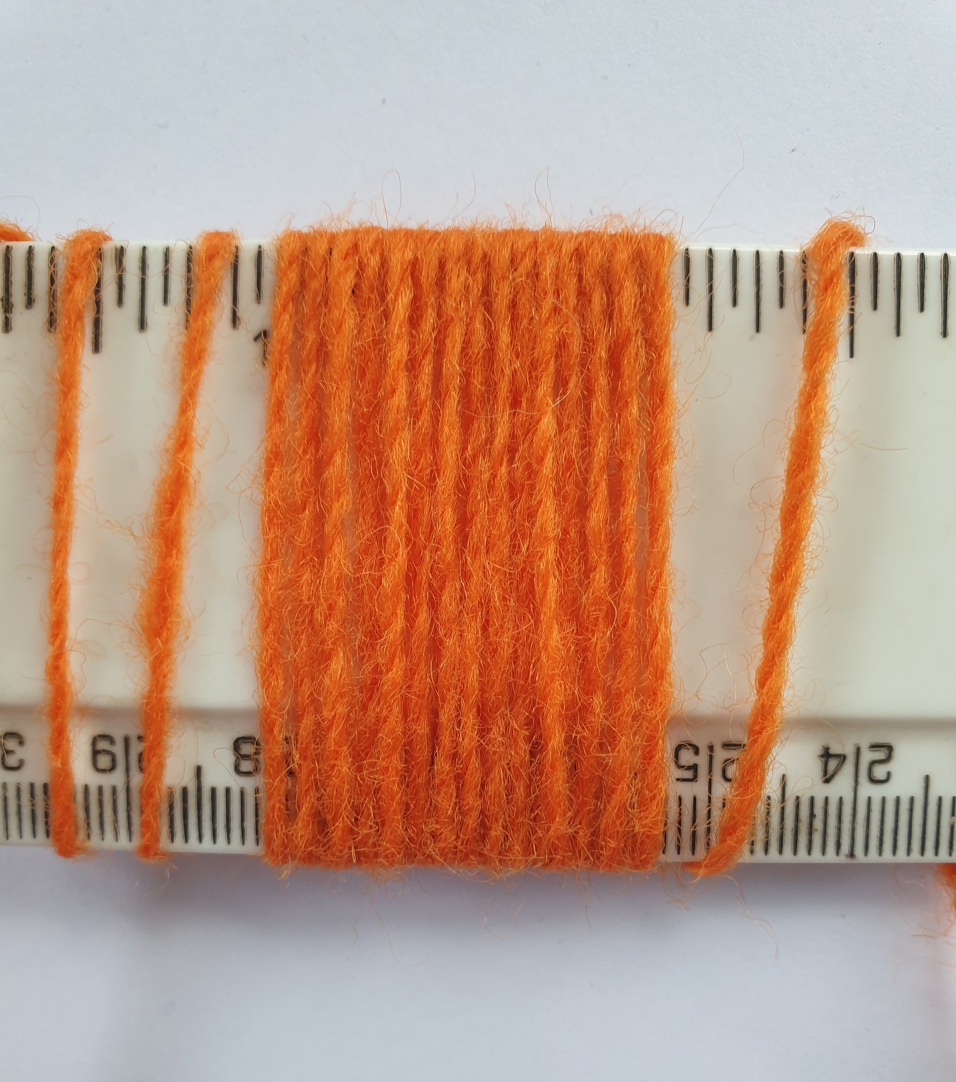 Orange rug yarn showing wraps per inch