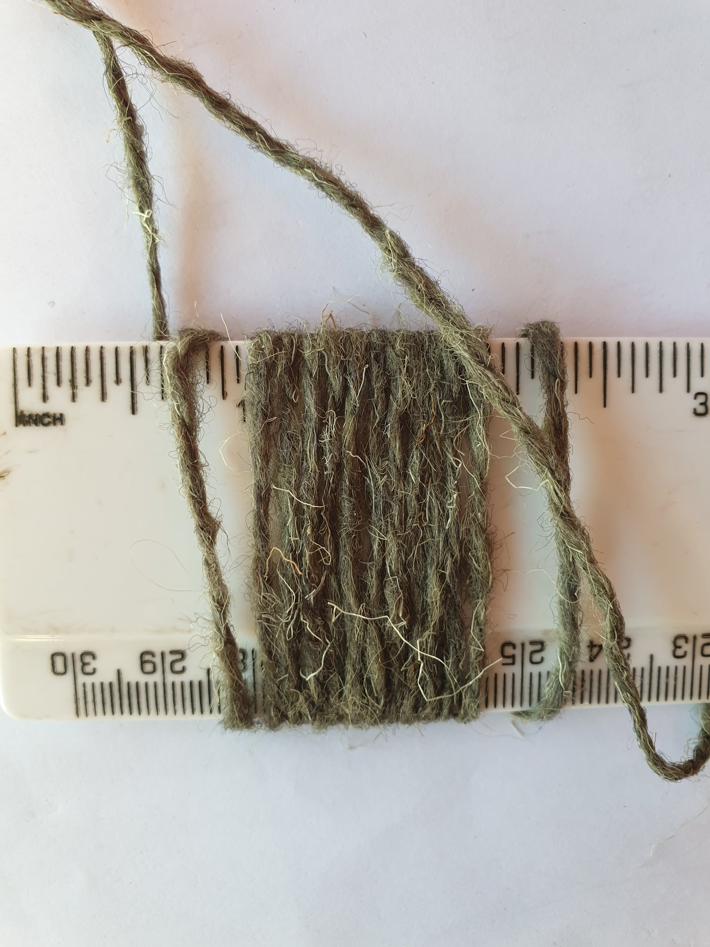 Dull green marram grass coloured rug yarn showing 11 wraps per inch