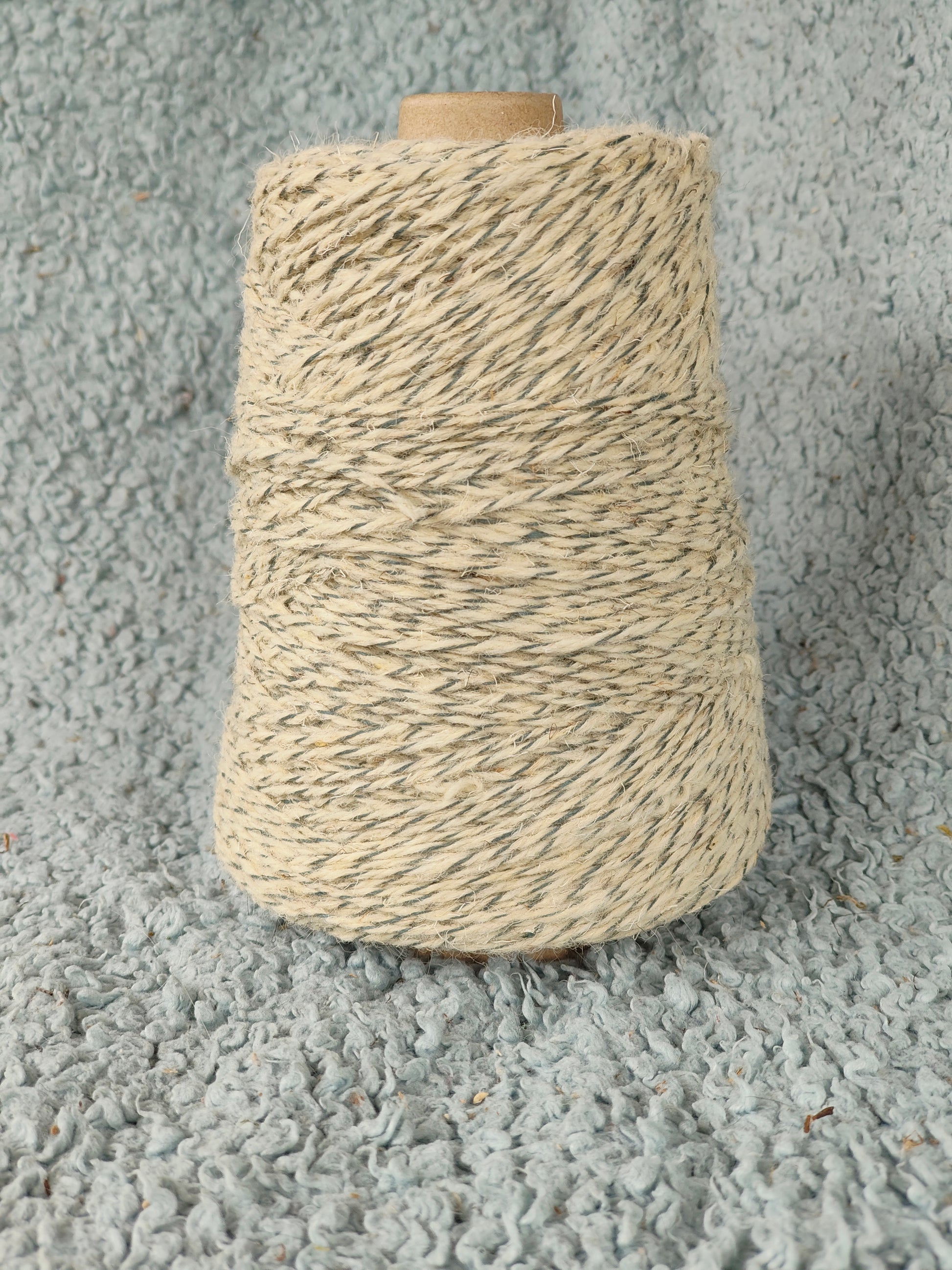 A 250g cone of two-tone grey and blue twisted rug yarn