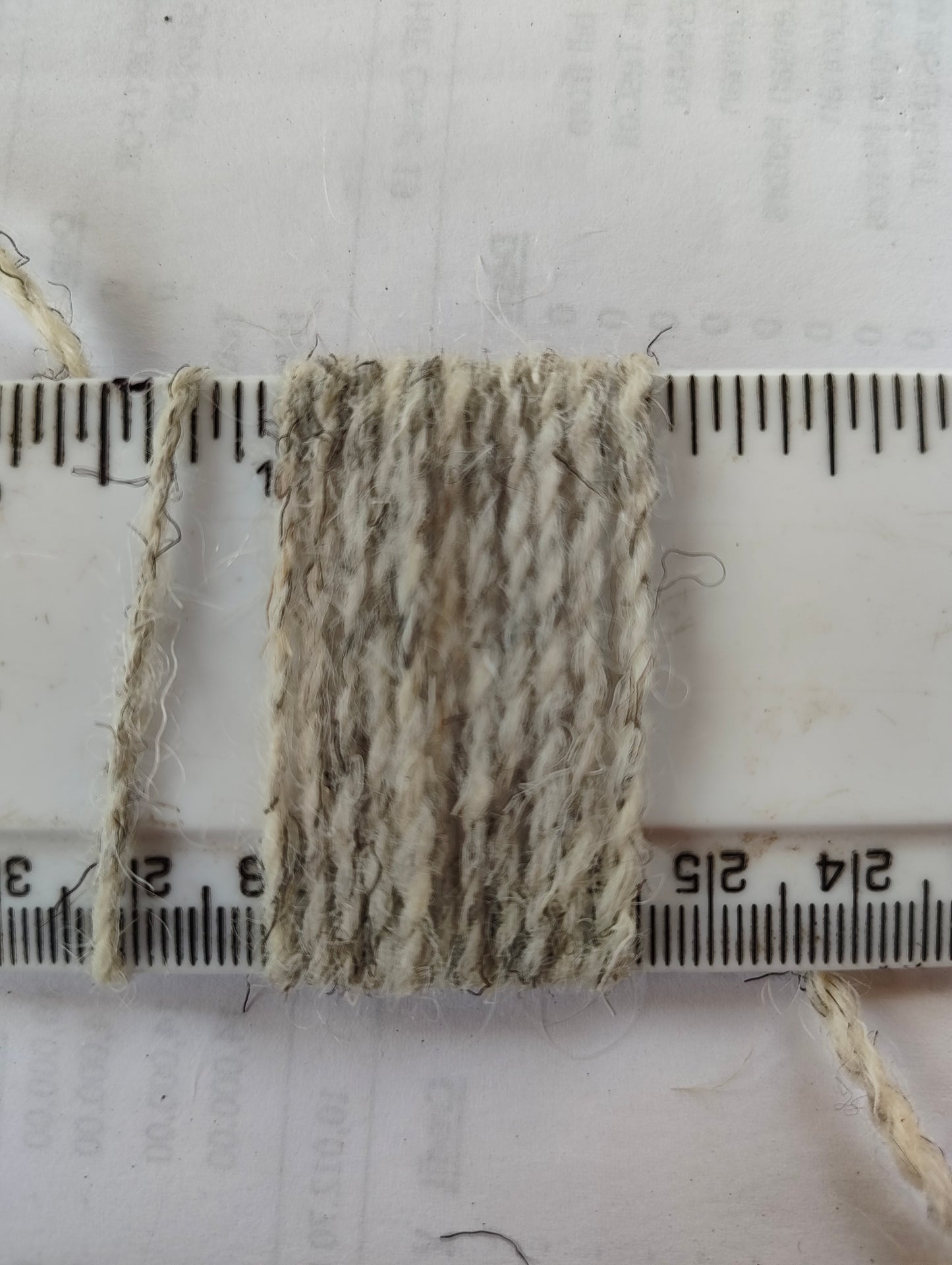 Light grey tweedy weaving yarn showing 11 wraps per inch