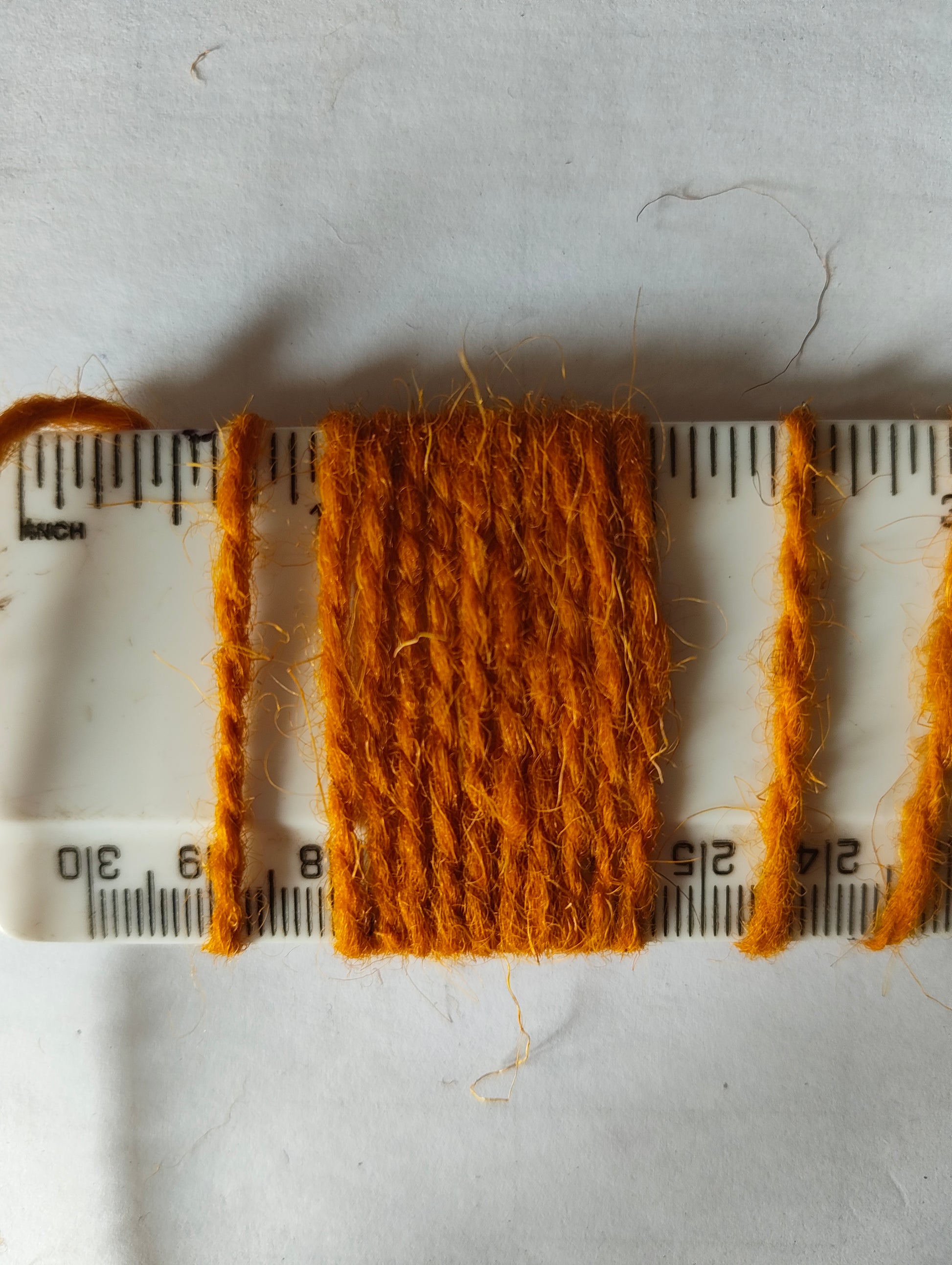 An oraney gold rug yarn showing 10 wraps per inch