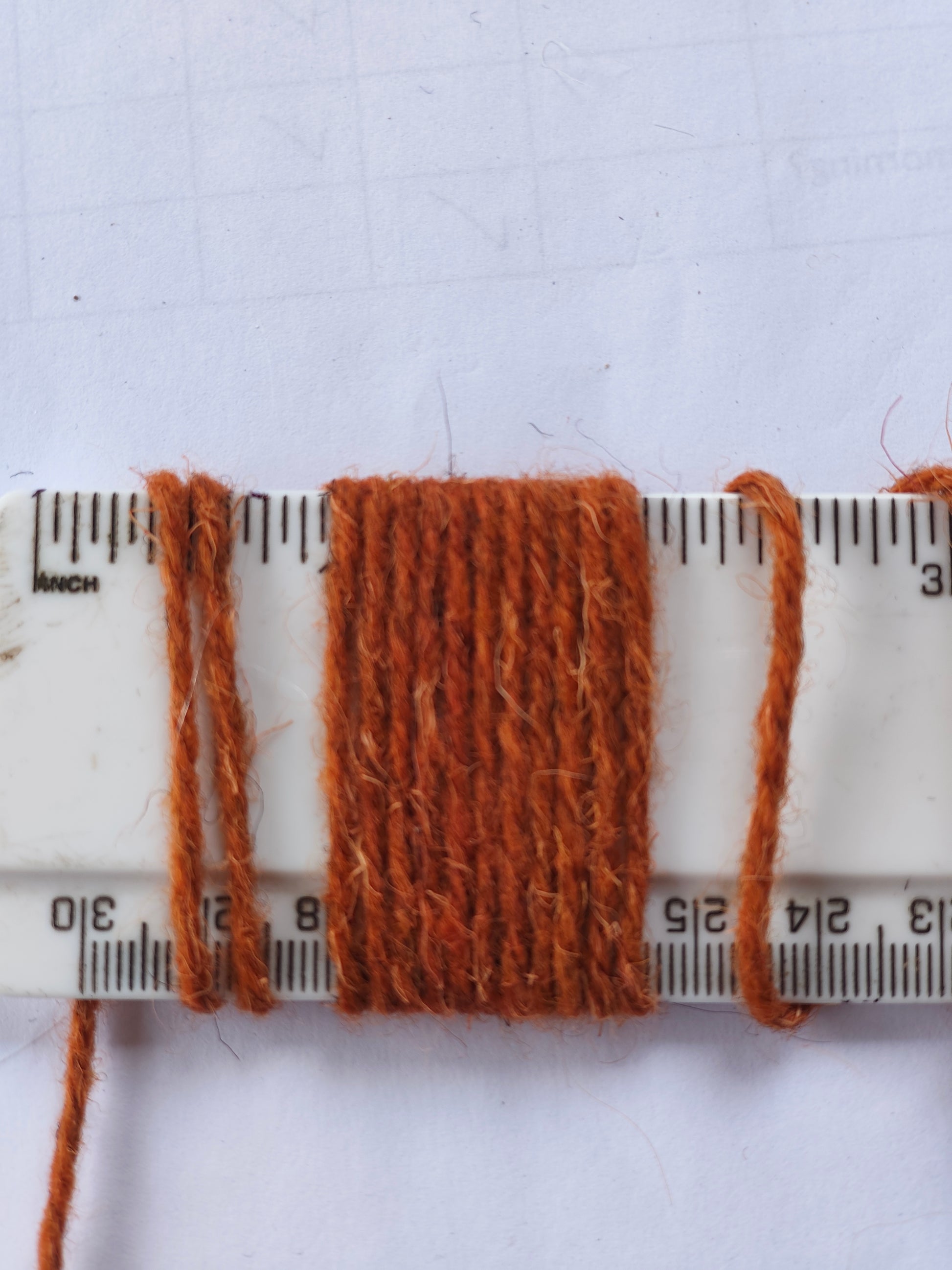 Rust-coloured rug wool showing 11 wraps per inch