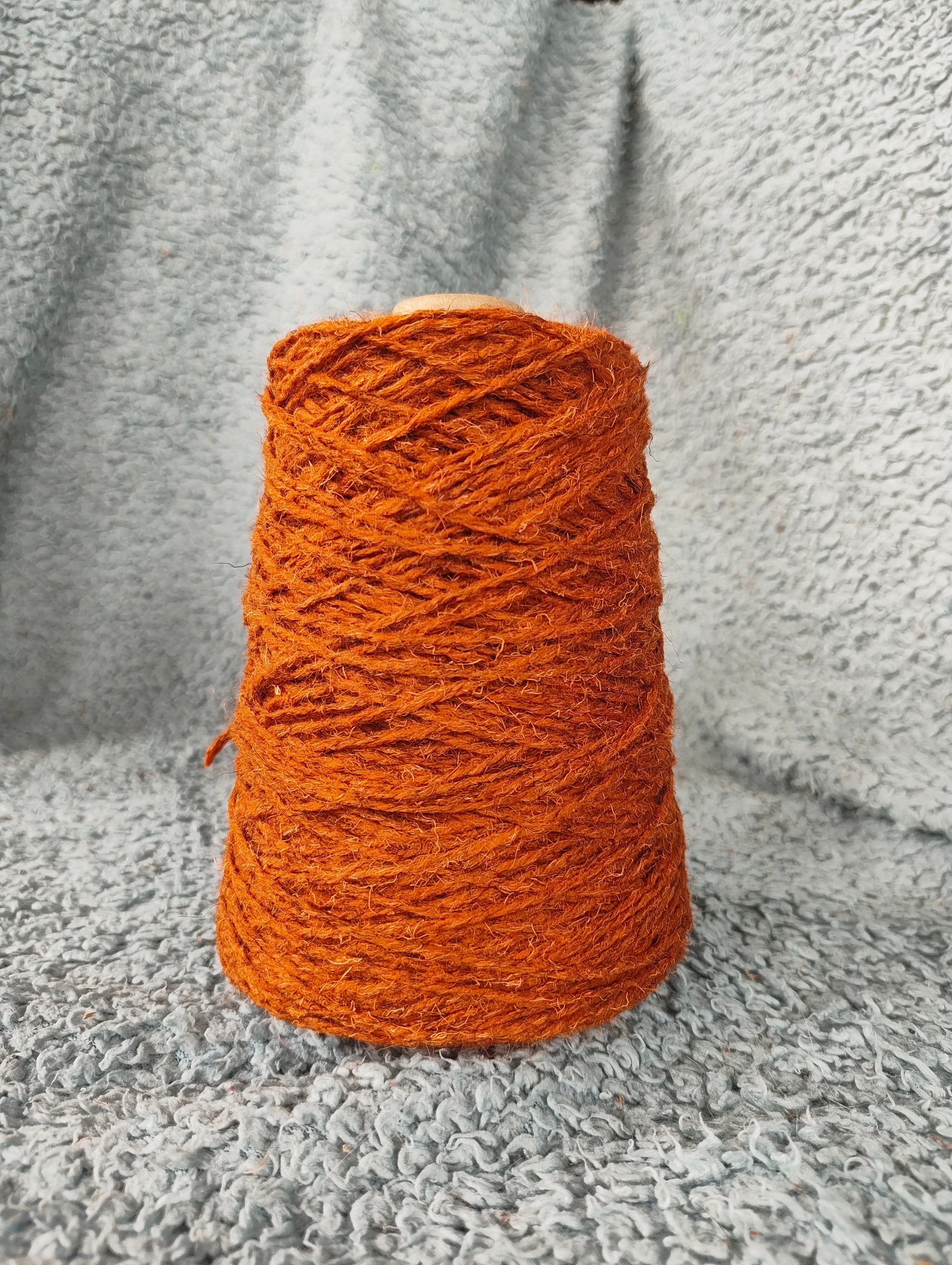 A rust-coloured cone of rug wool for weaving