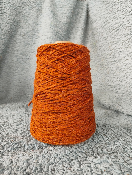 A rust-coloured cone of rug wool for weaving
