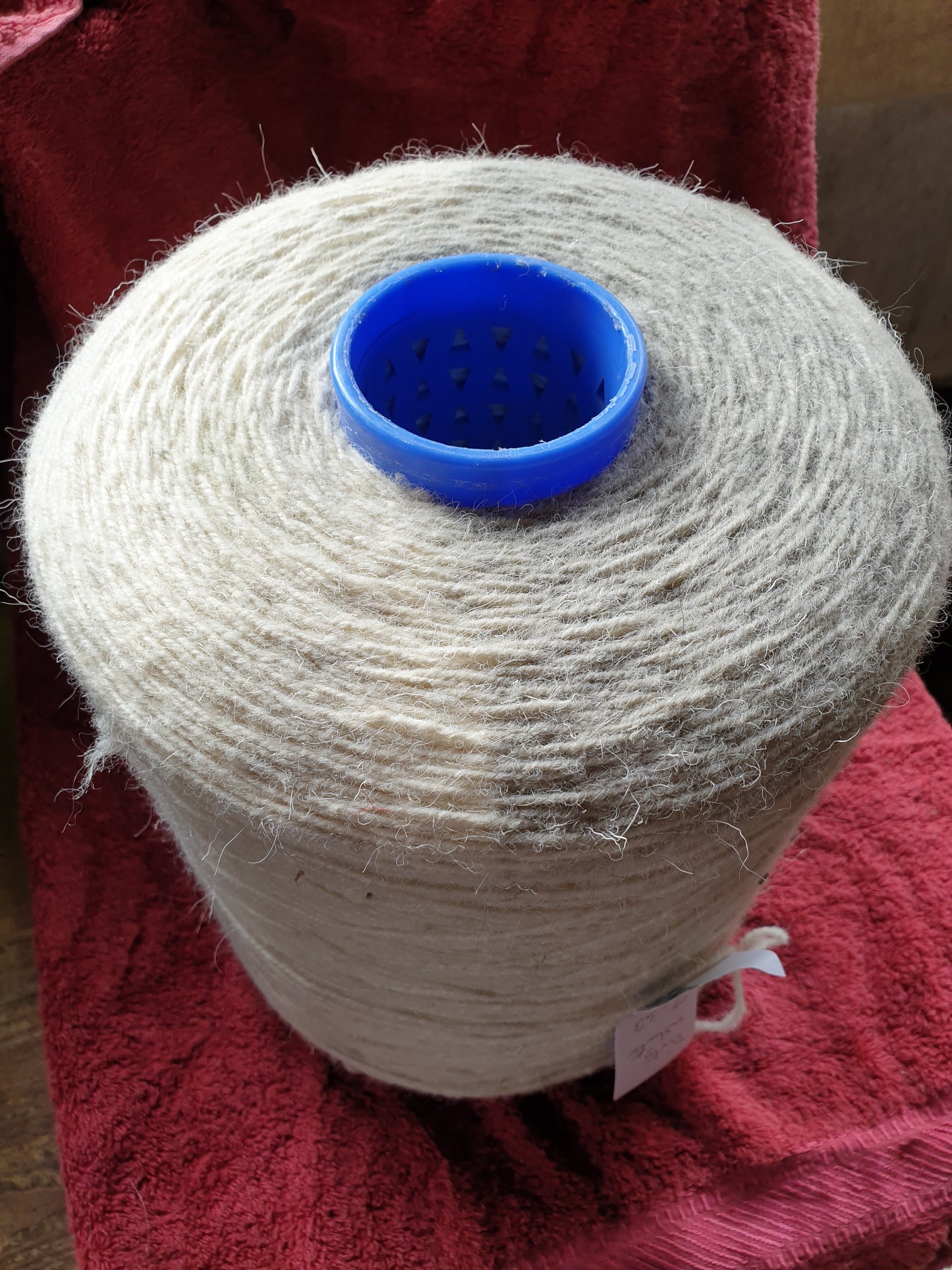 A large cone of white rug wool showing some discolouration