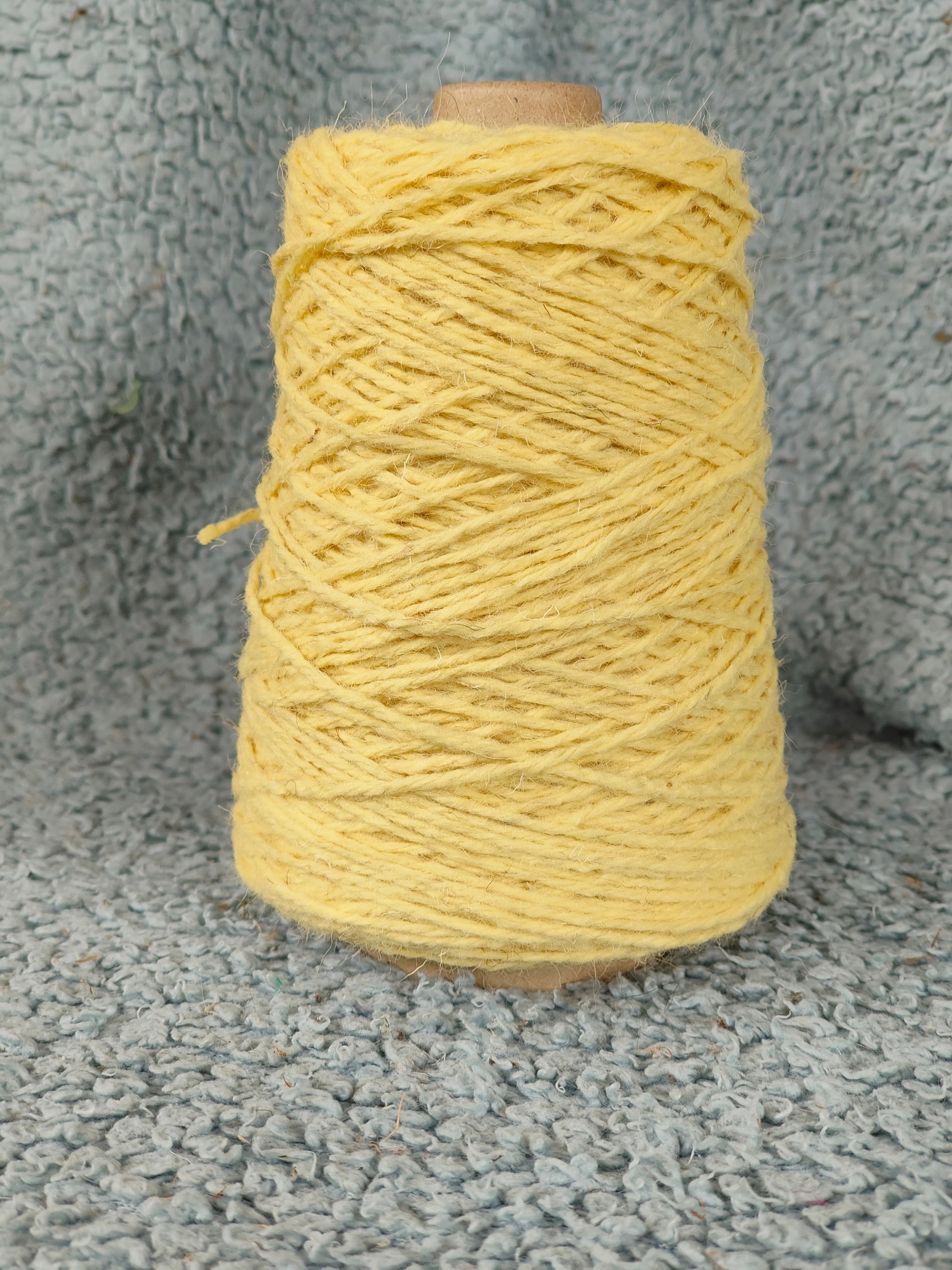 A cone of yellow rug yarn for weaving