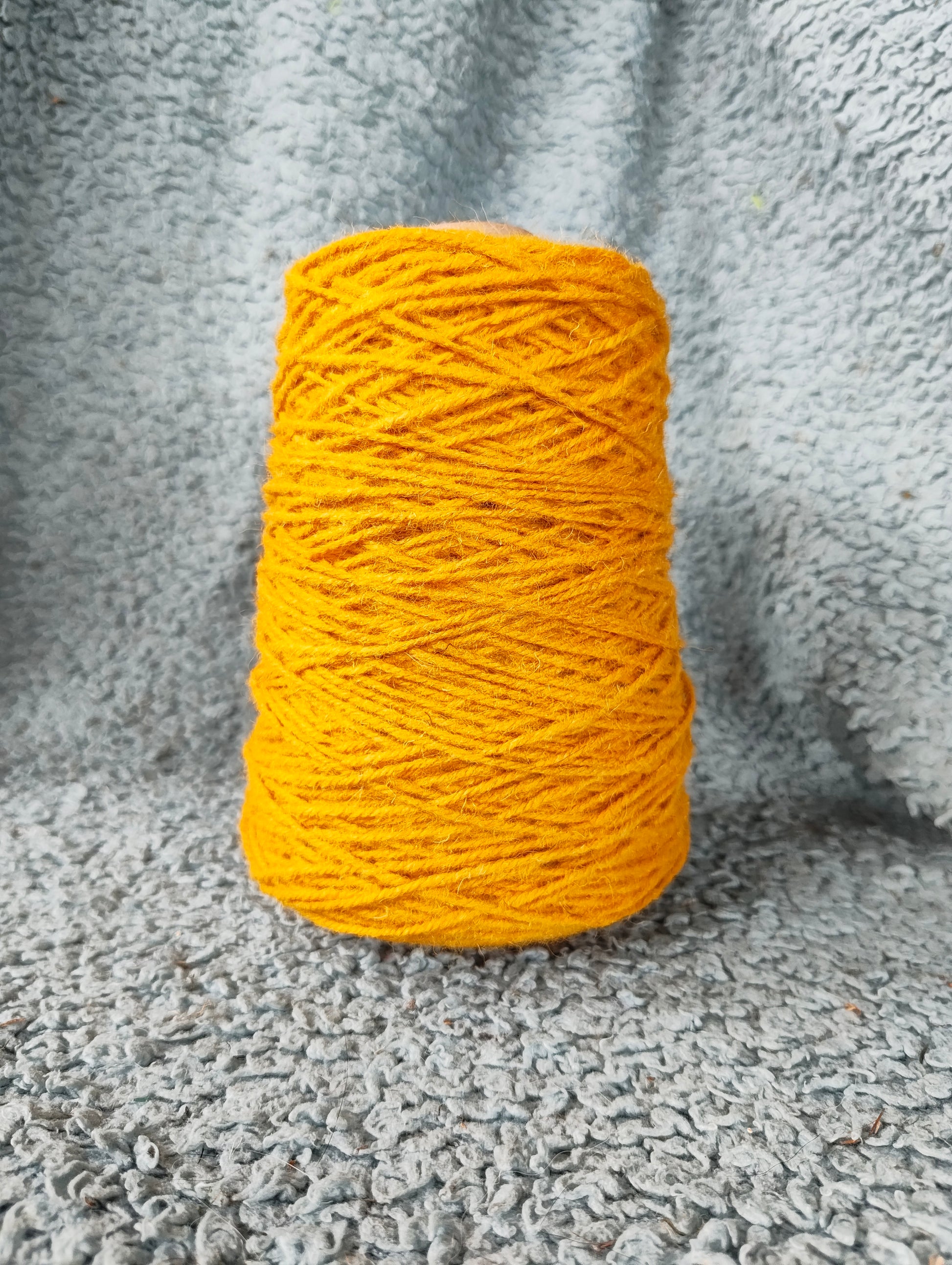 A cone of corn-coloured Axminster rug yarn