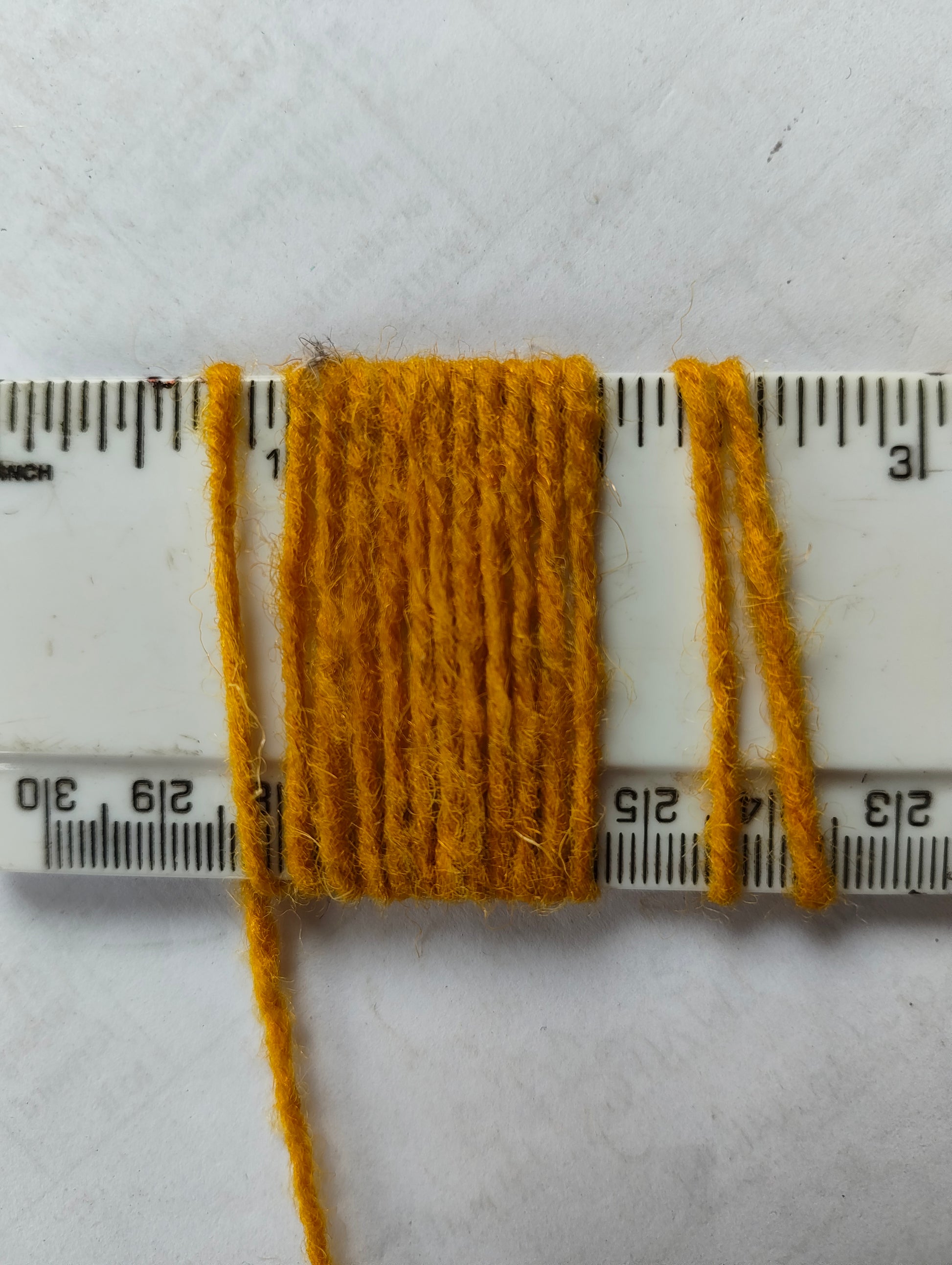Corn-coloured rug yarn showing 11 wraps per inch