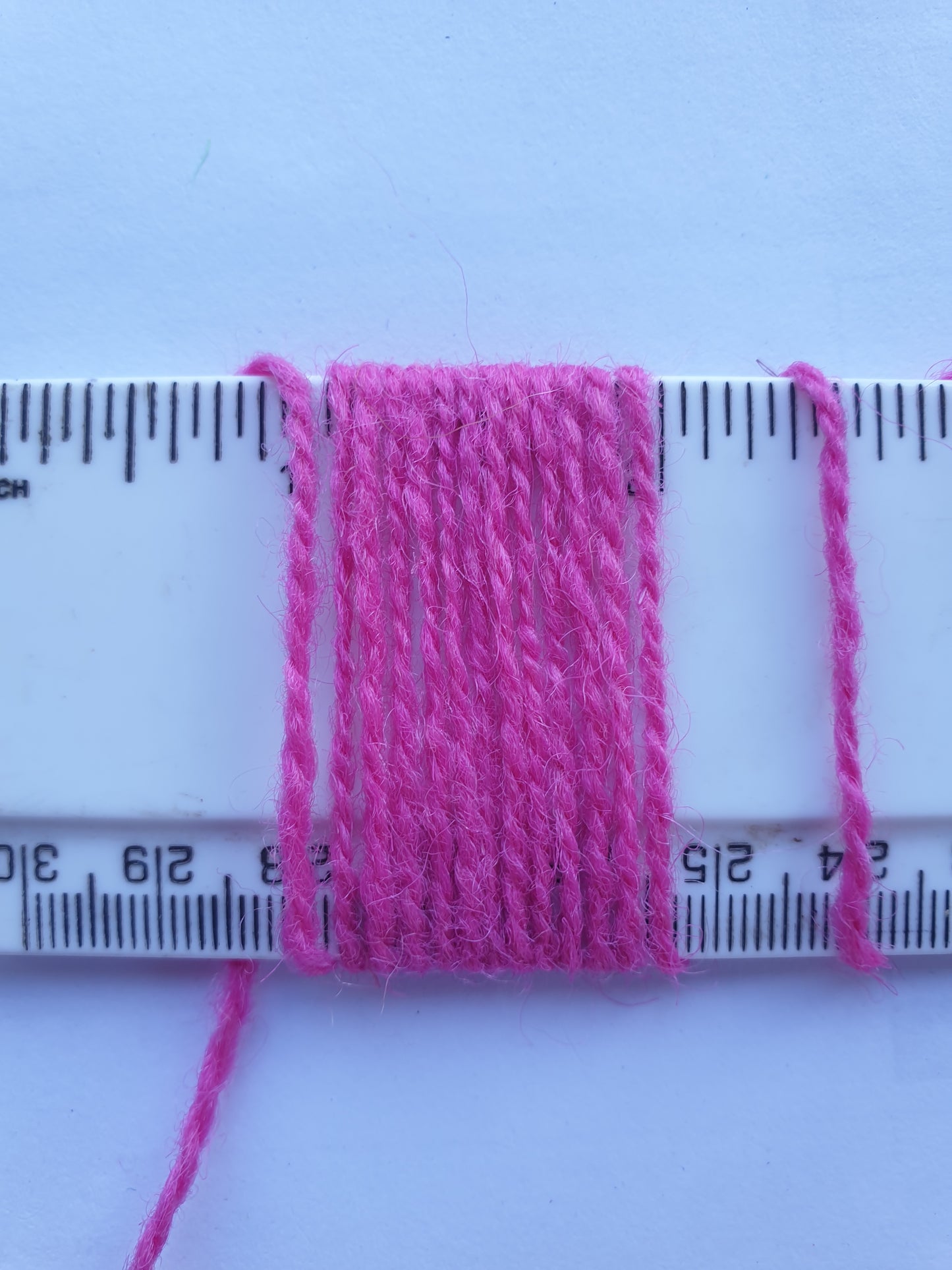 Cerise Rug Yarn showing wraps per inch