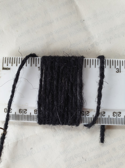 A natural black rug wool showing 11 wraps per inch