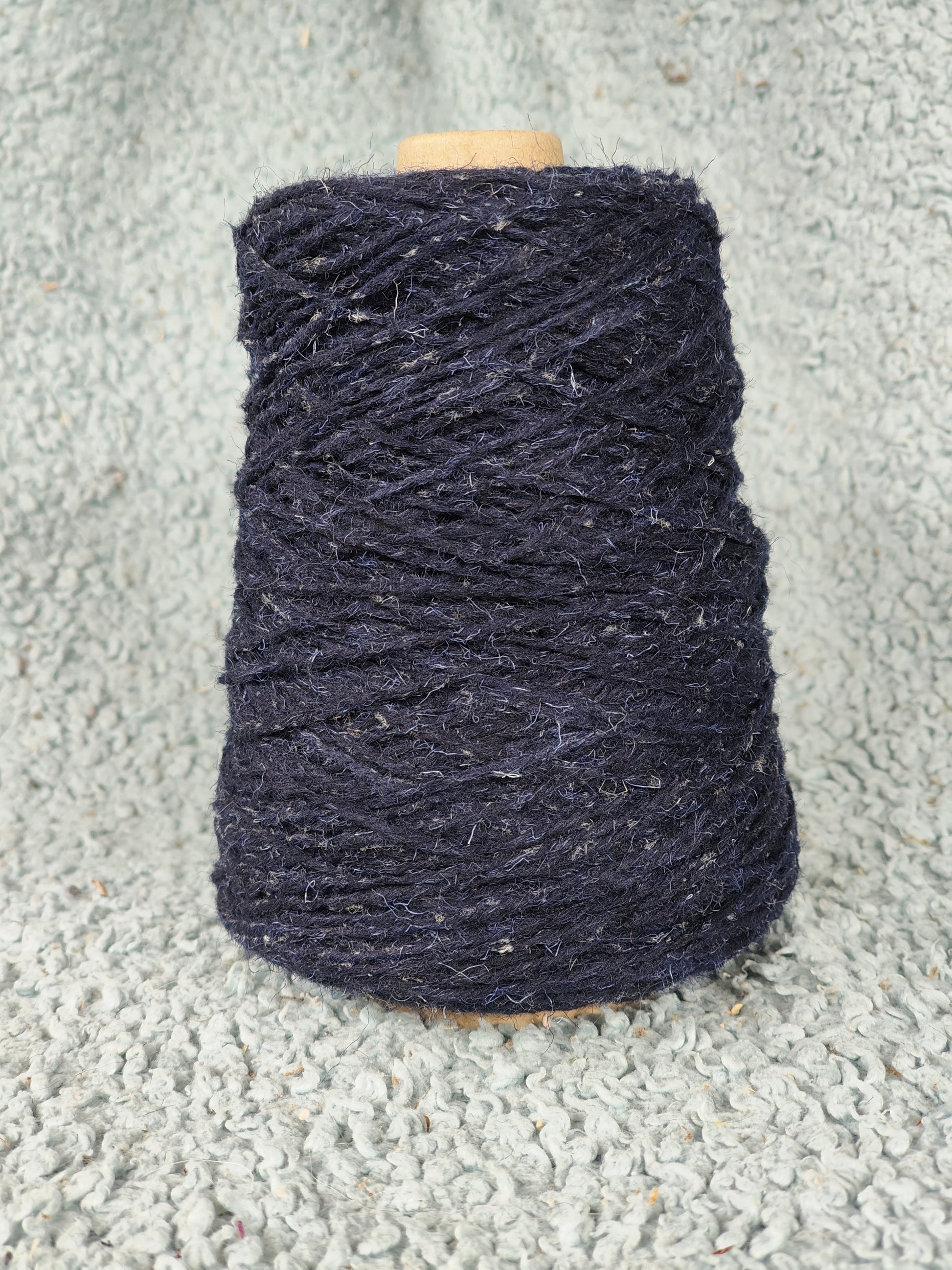 A cone of starlight flecked blue rug yarn