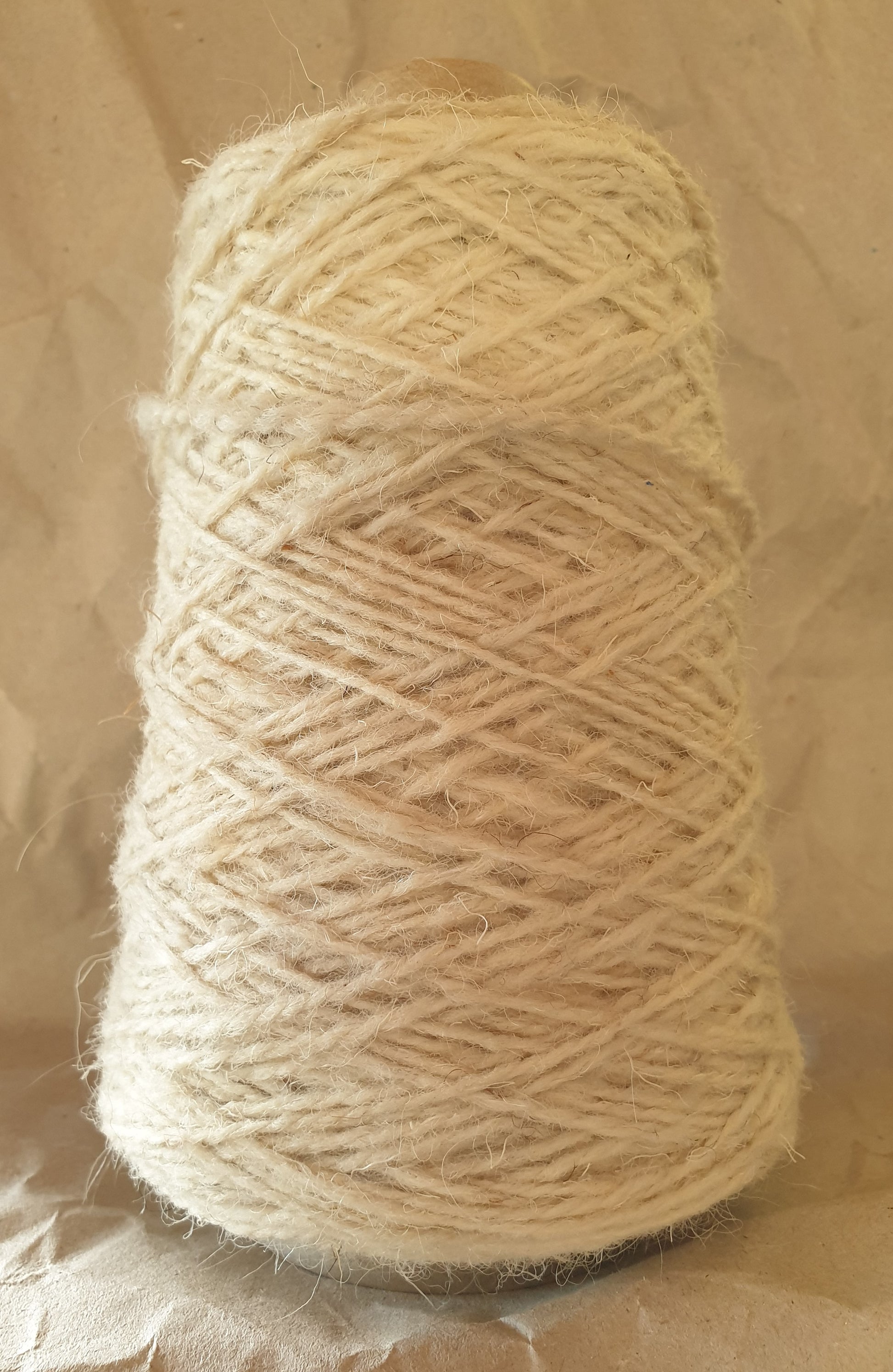 A cone of cream rug yarn for weaving, tufting or crochet