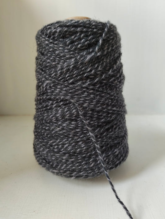 A 250g cone of light and dark grey twisted weaving yarns