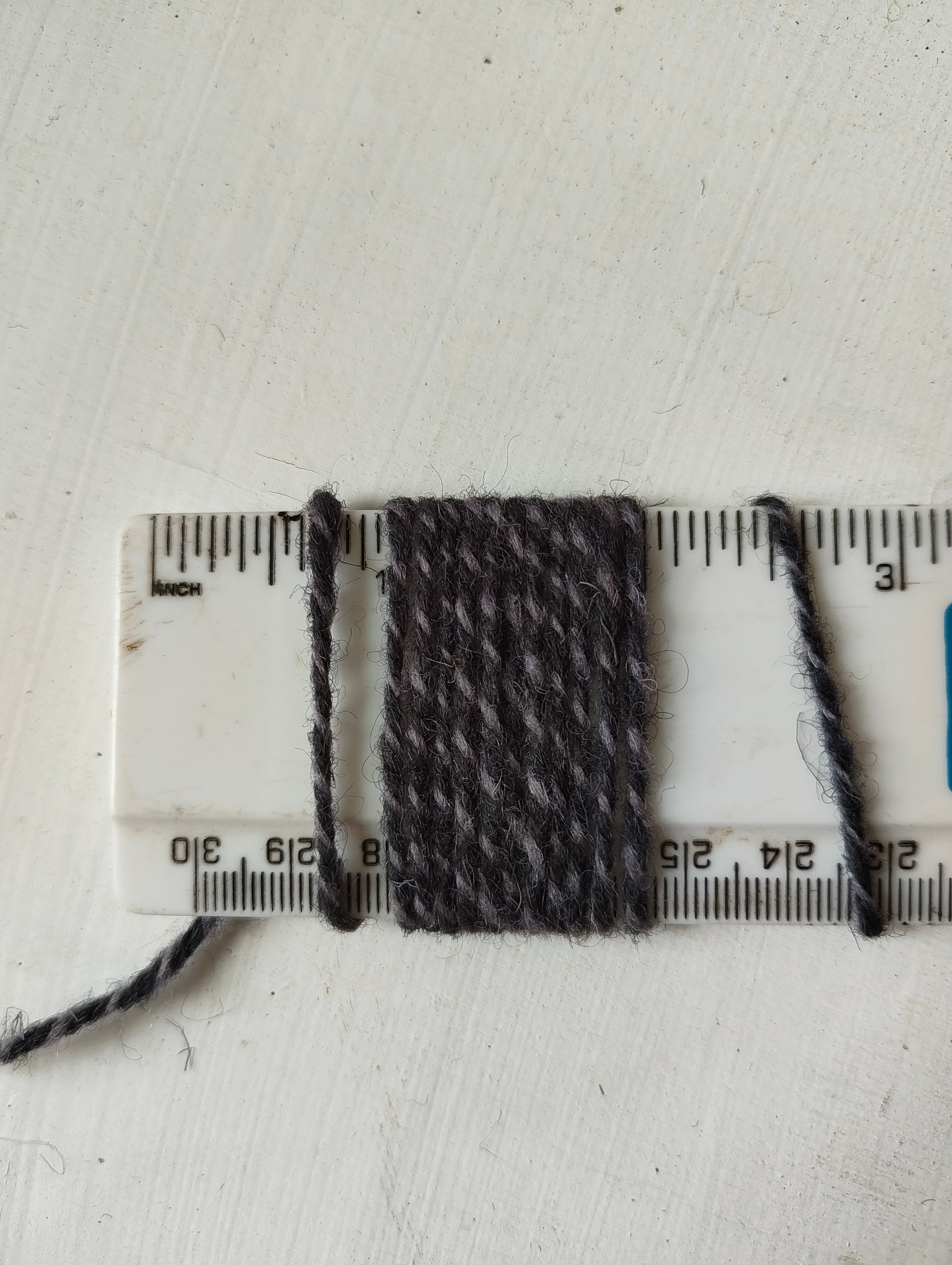 Light and Dark grey twisted rug yarns showing a thickness of 11 wraps per inch