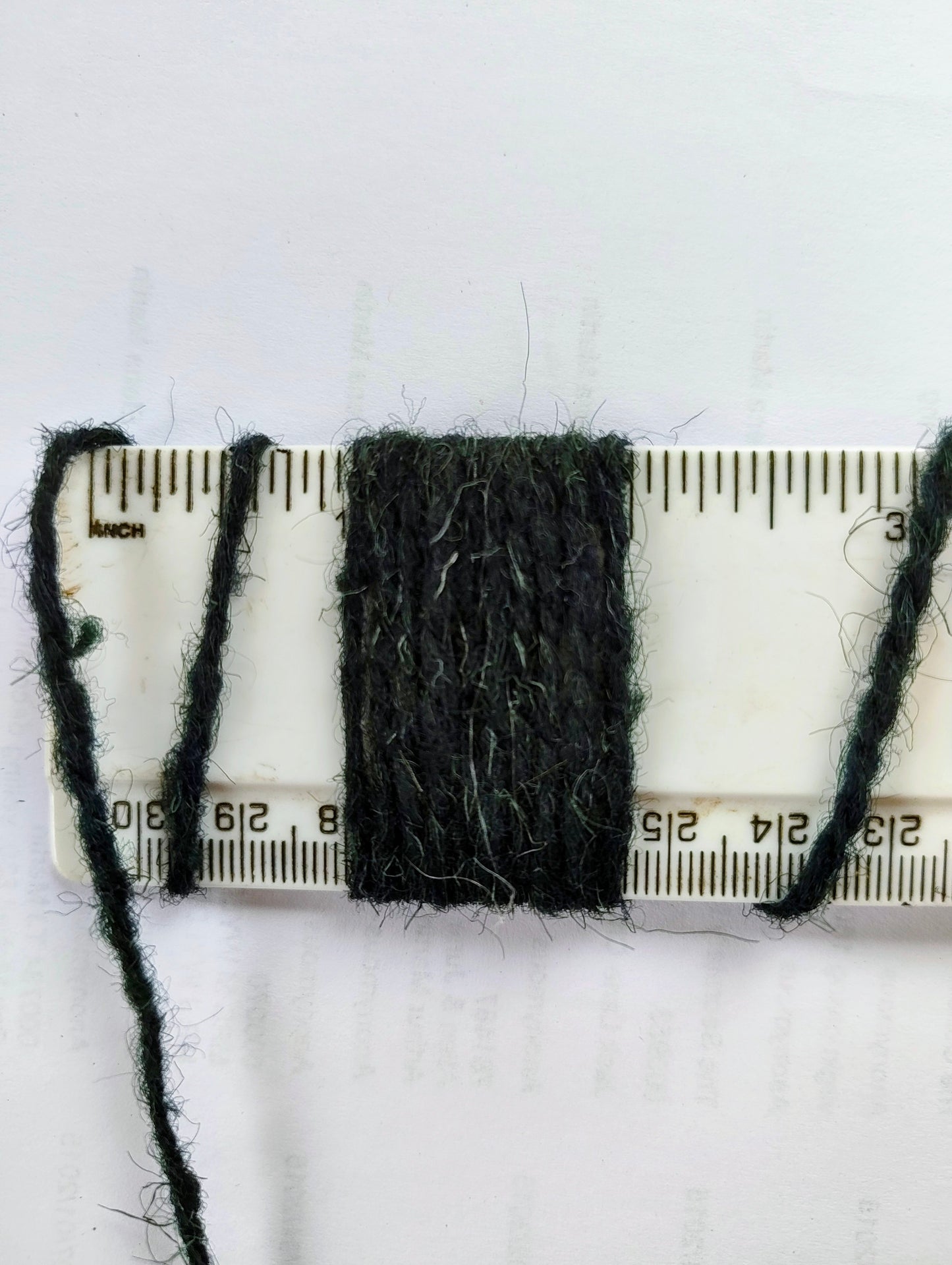 Dark green rug yarn showing 10 wraps per inch