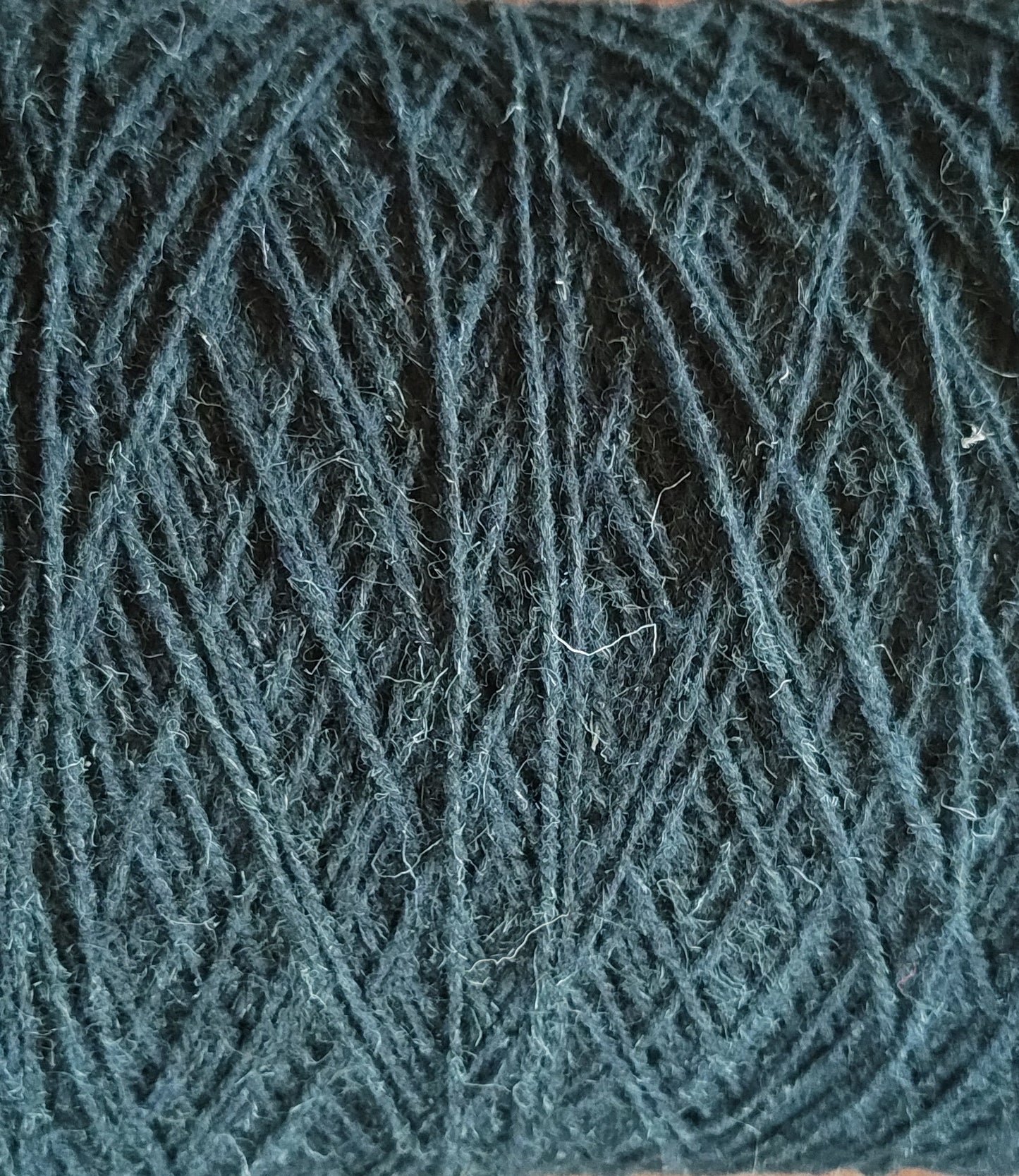 A close up of dark green rug yarn for weaving or tufting 