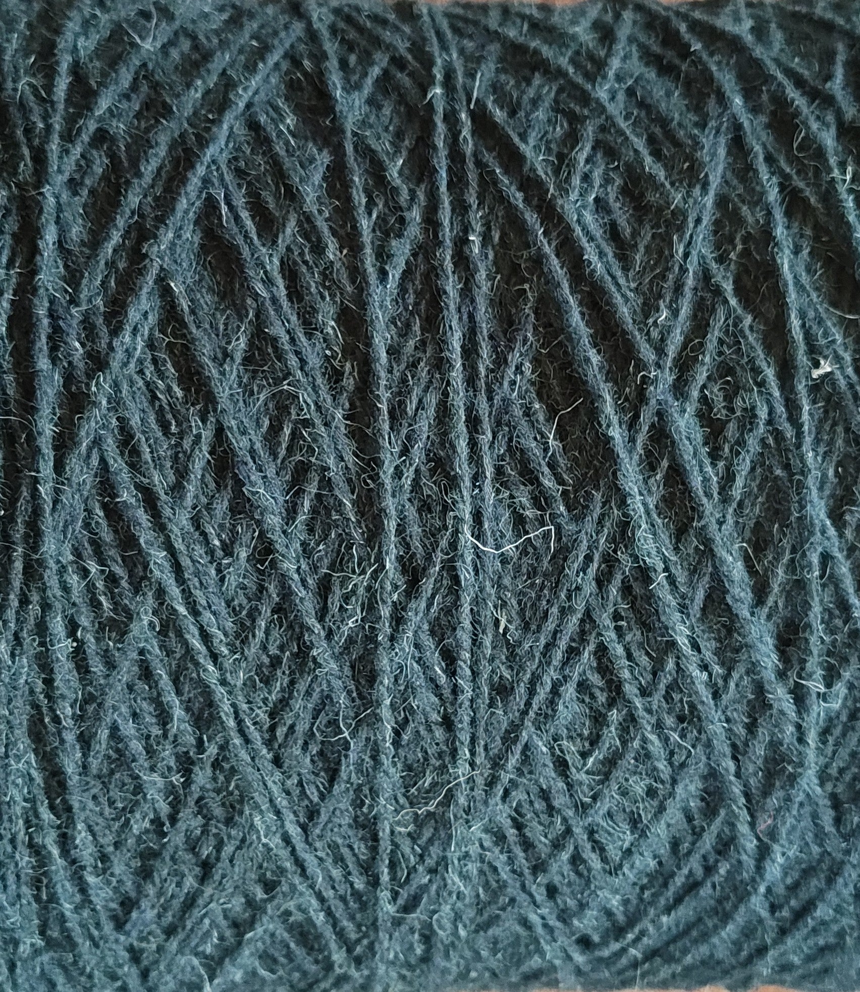 A close up of dark green rug yarn for weaving or tufting 