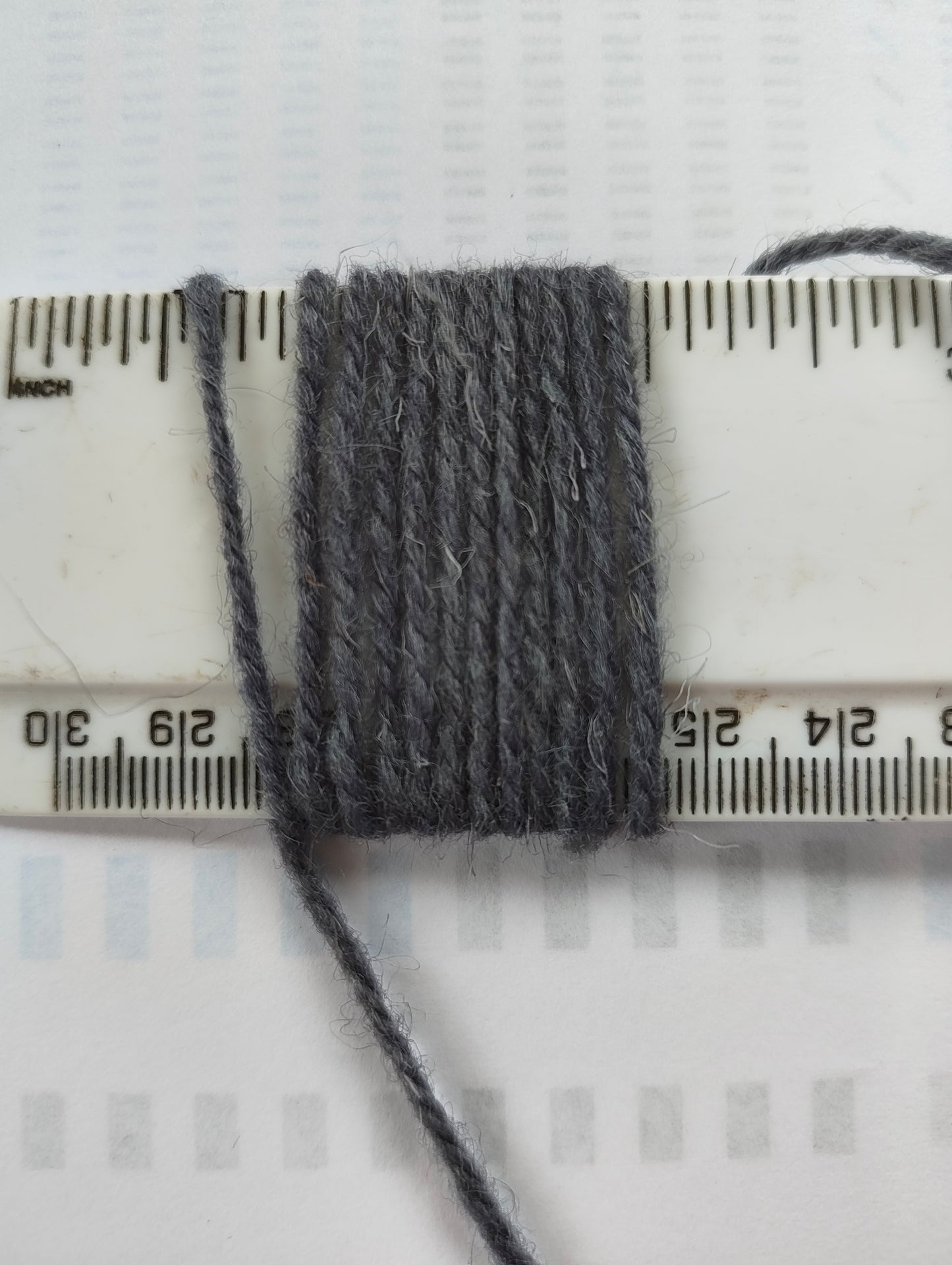 A medium thickness bluey grey rug yarn showing 11 wraps per inch