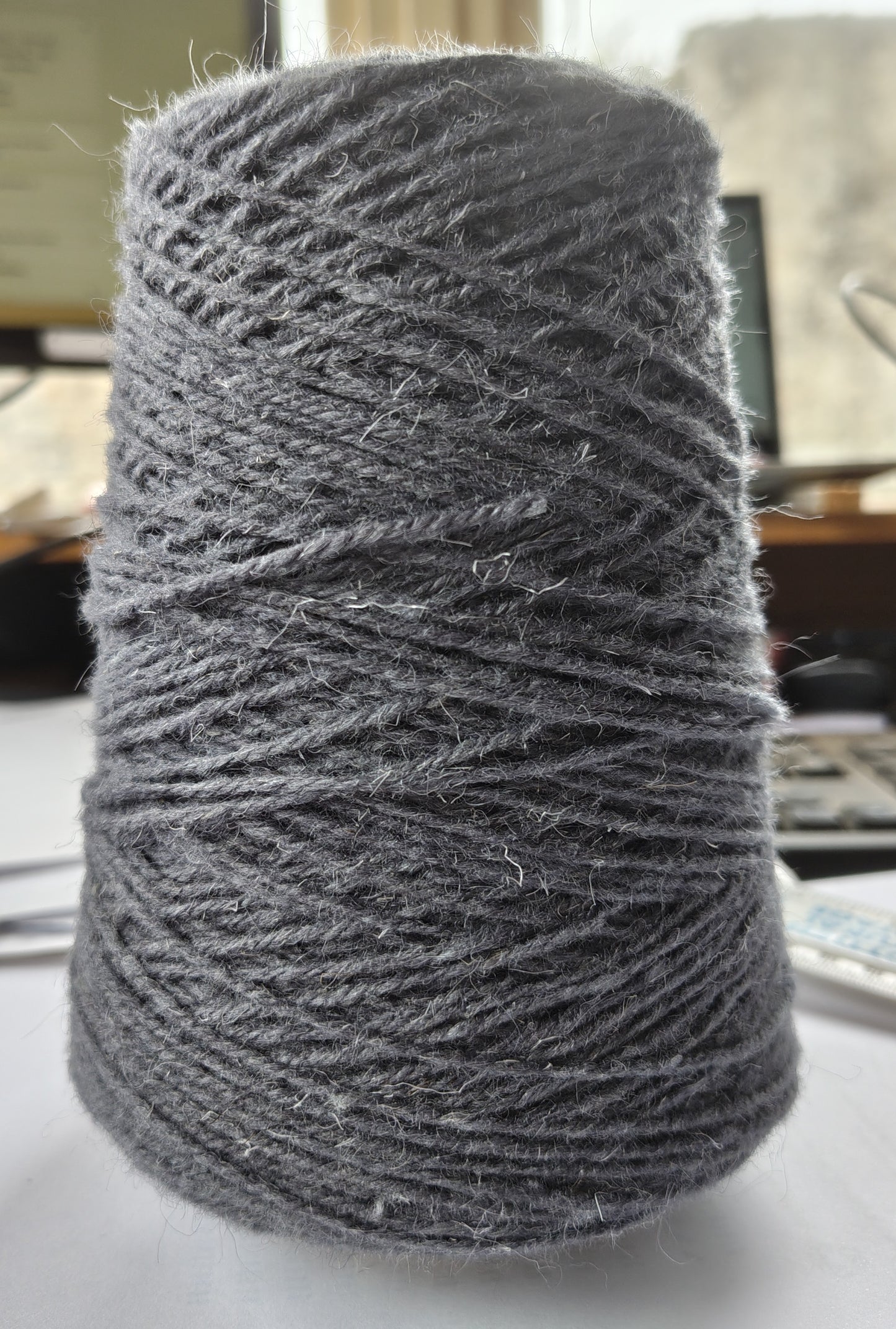A cone of bluey grey rug yarn for weaving, tufting etc