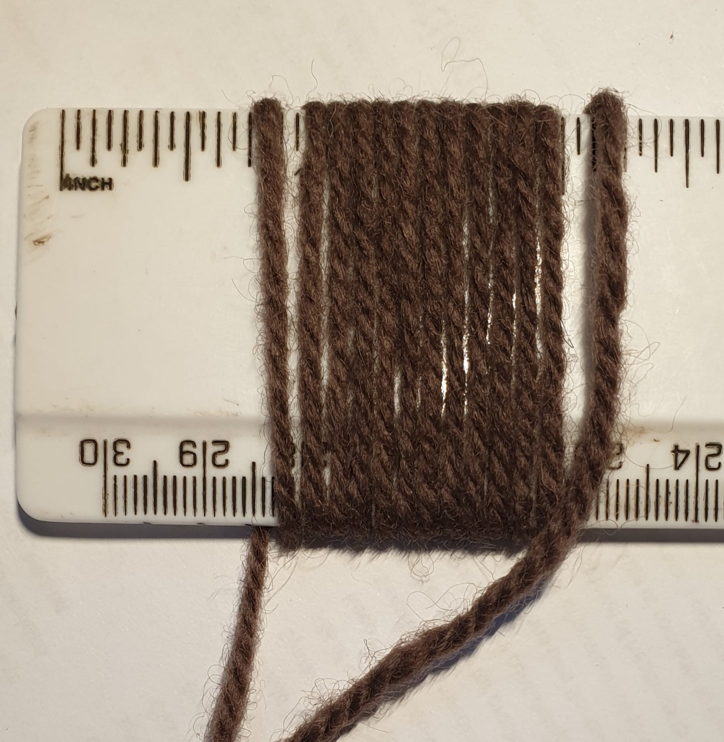 Mauve brown rug yarn showing wraps per inch