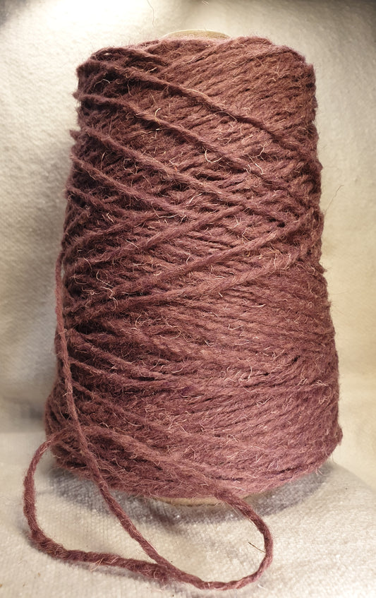 a cone of dark mauve rug yarn