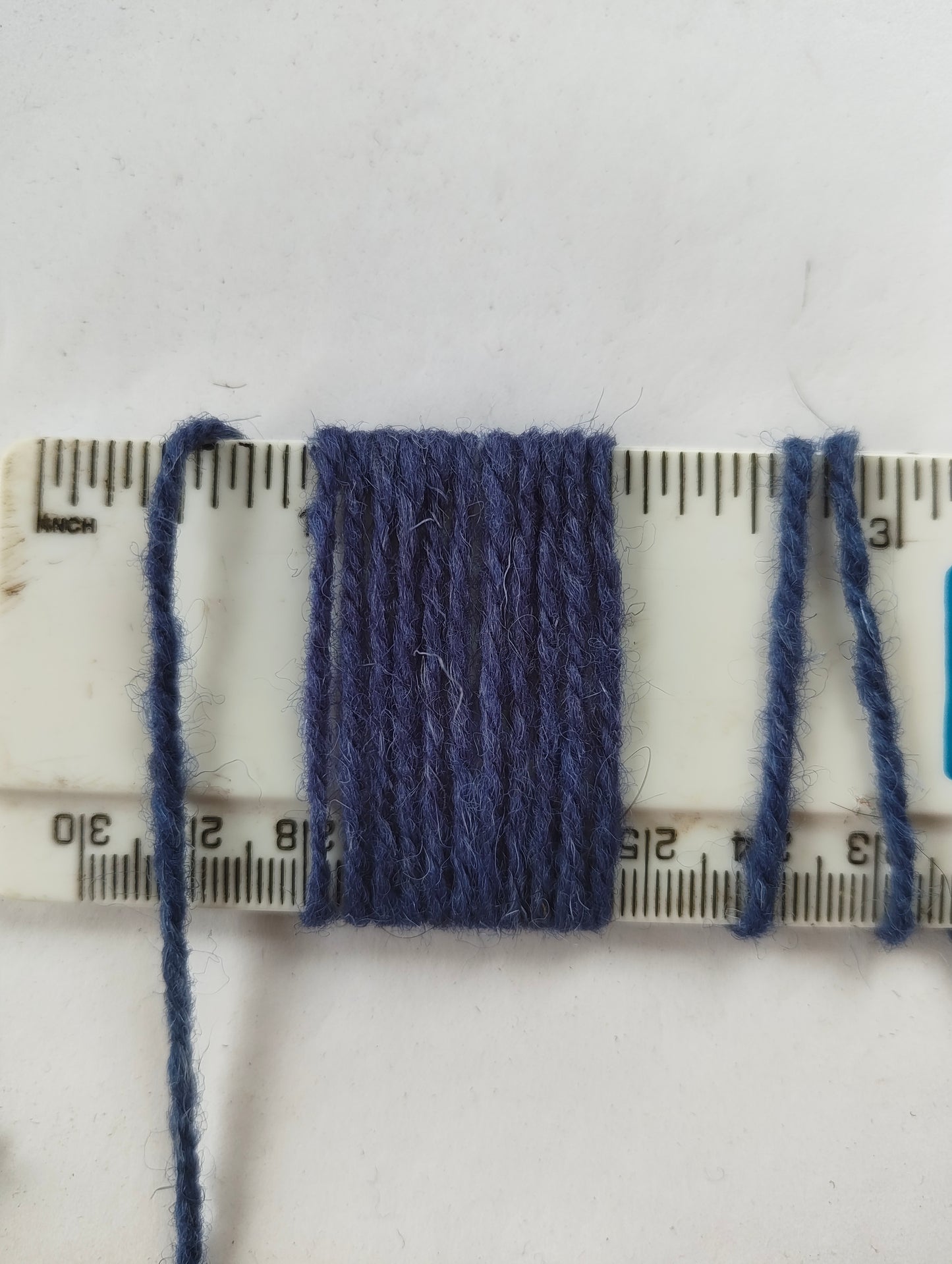 A medium blue rug yarn showing 11 wraps per inch thickness