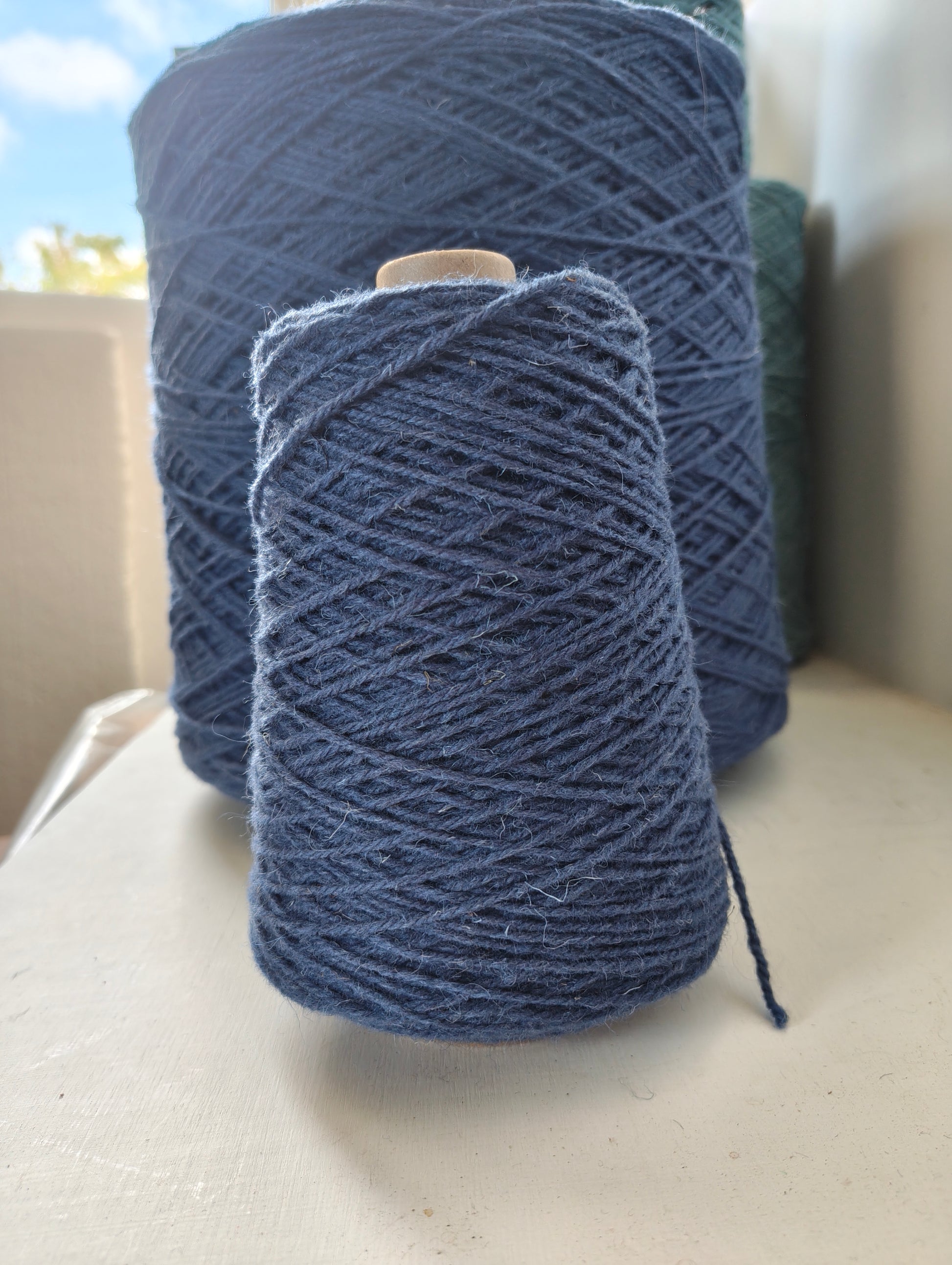 a cone of medium blue weaving yarn