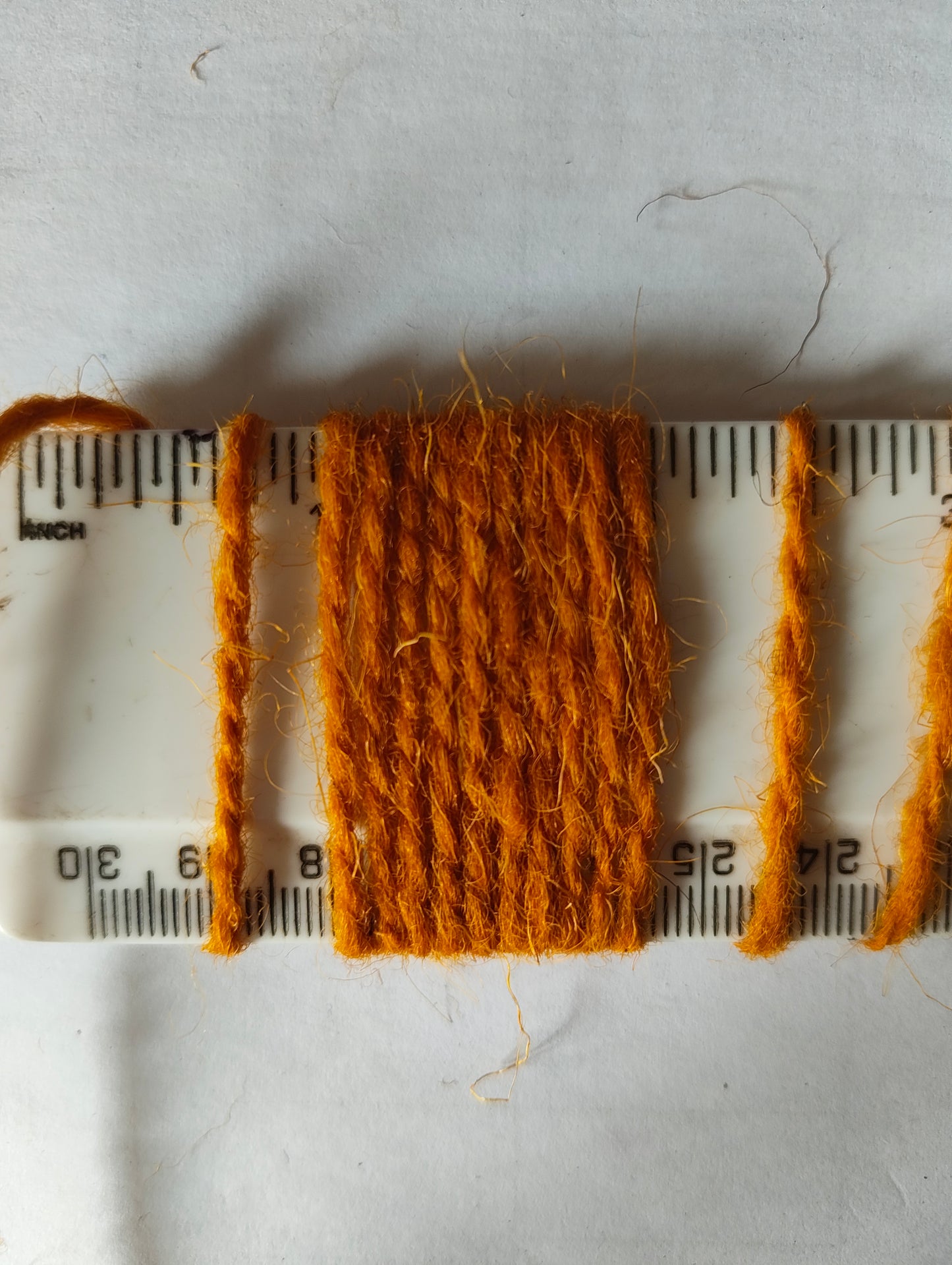 An oraney gold rug yarn showing 10 wraps per inch