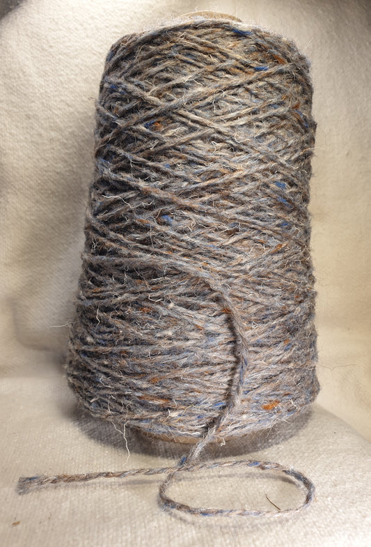 A cone of tweedy blue rug yarn