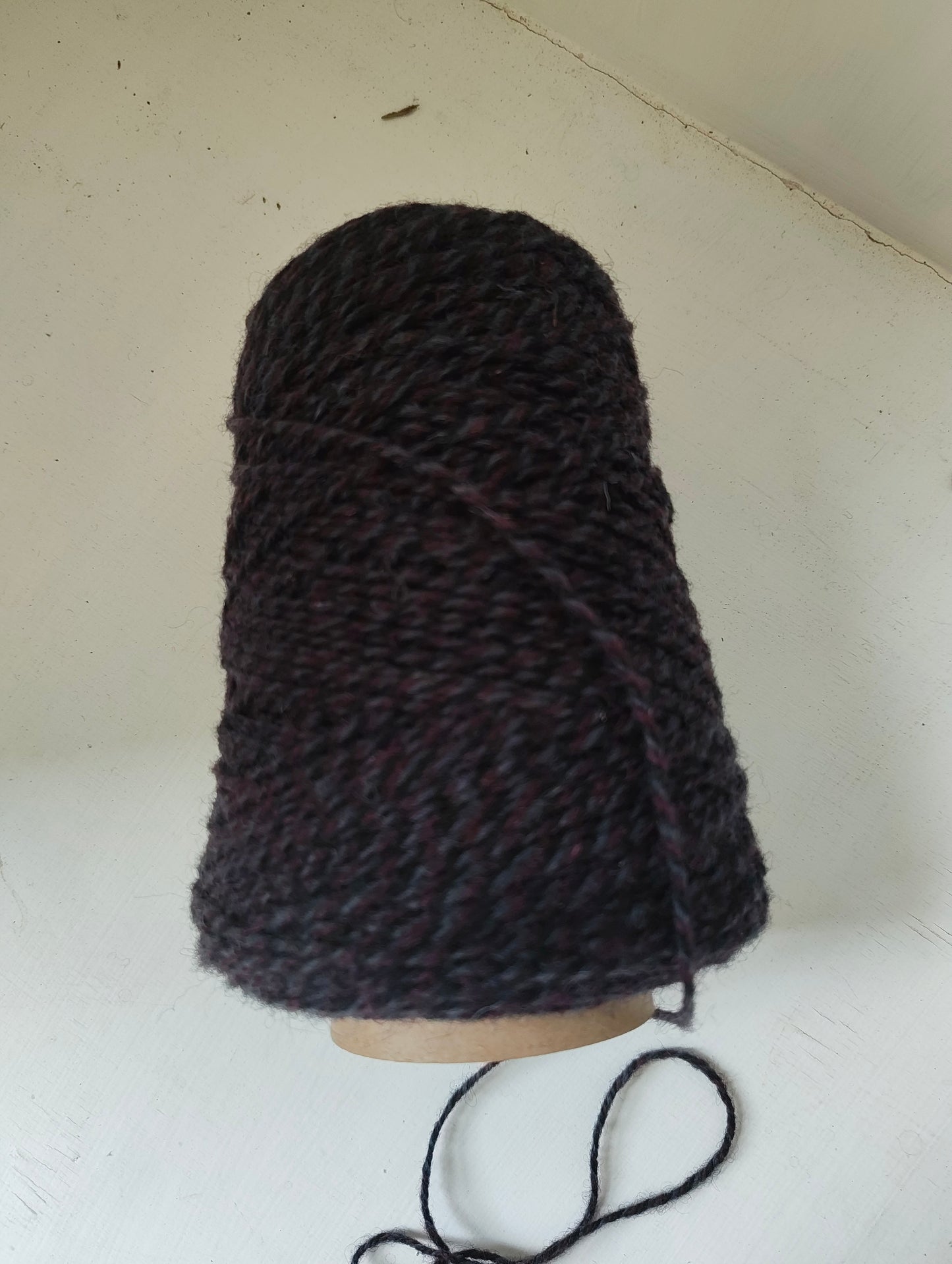 A cone of purple triple twist weaving yarn