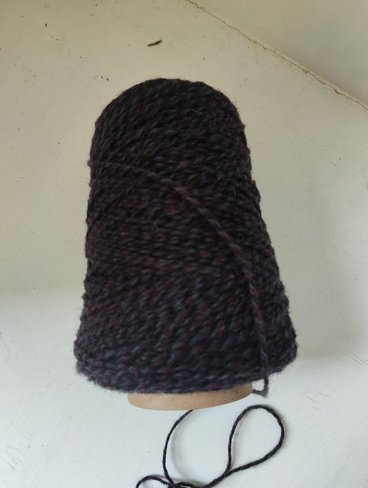 A cone of purple triple twist weaving yarn