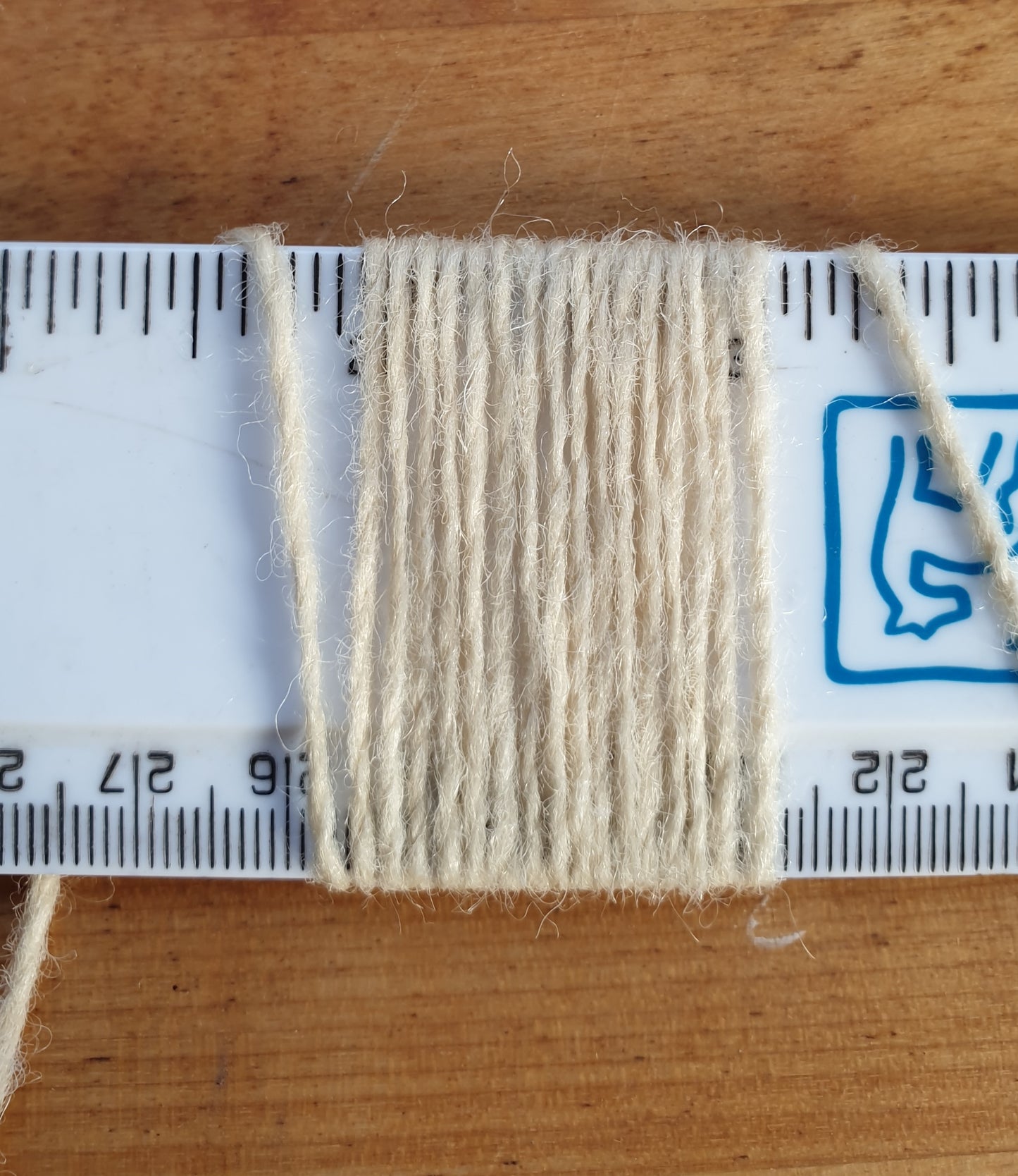 Thin cream rug yarn showing wraps per inch