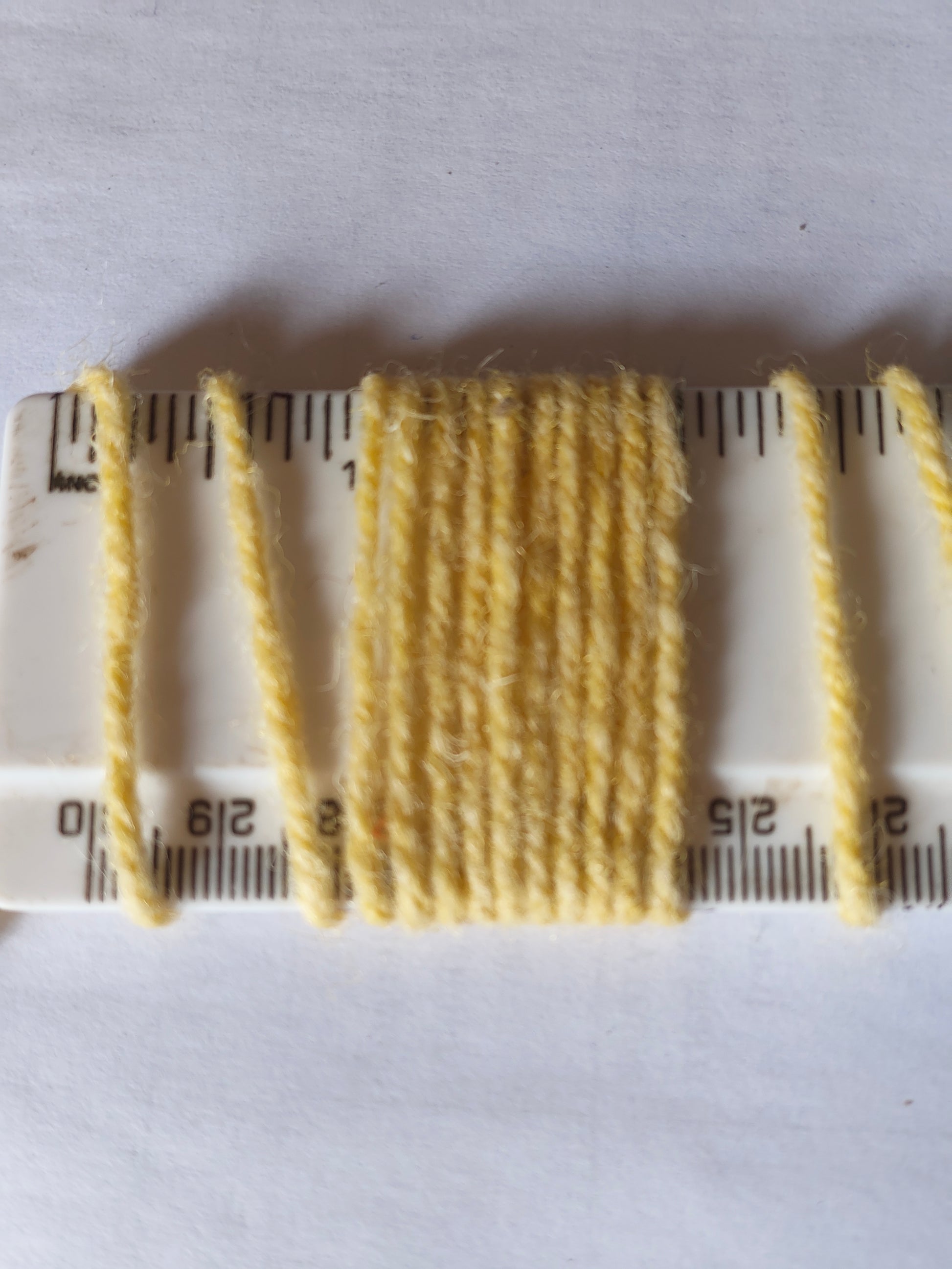 Pale yellow axminster rug yarn showing 10 wraps per inch