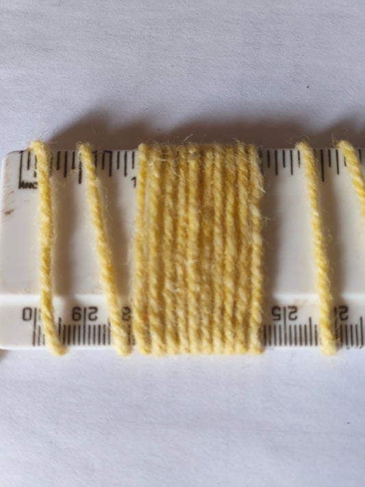 Pale yellow axminster rug yarn showing 10 wraps per inch