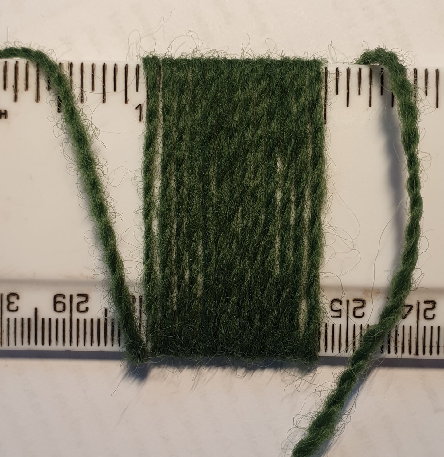 Bayleaf green rug yarn showing wraps per inch